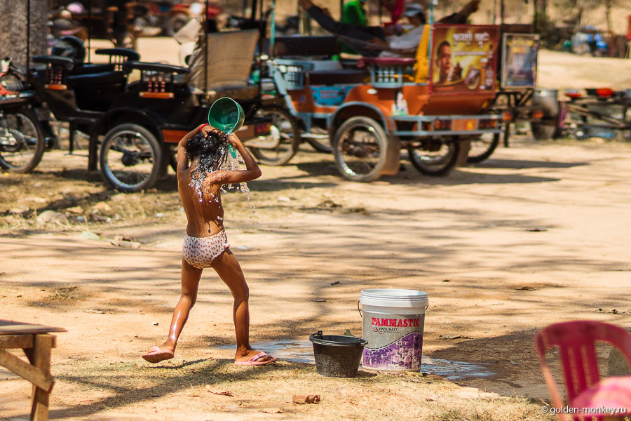 Камбоджийский ребенок поливается водой, Ангкор, Камбоджа.